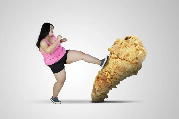饮食概念 穿着运动服的胖女人 在打炸鸡大腿的时候 在白色背景上被隔离 — 图库照片