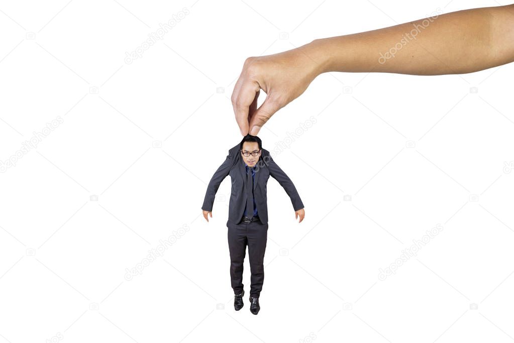 Picture of a young Asian businessman being lifted by big hand in the studio, isolated on white background