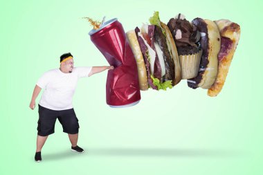 Yeşil ekran arka planda sağlıksız gıdalar Delme sırasında spor giyim giymiş bir Asya obez adam resmi