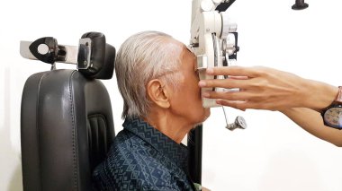 Side view of young doctor examining his patient eyes by using a phoropter, isolated on white background clipart