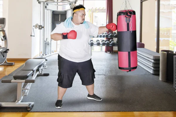 太りすぎの男ボクシング バッグをパンチとジム センターで運動のイメージ — ストック写真