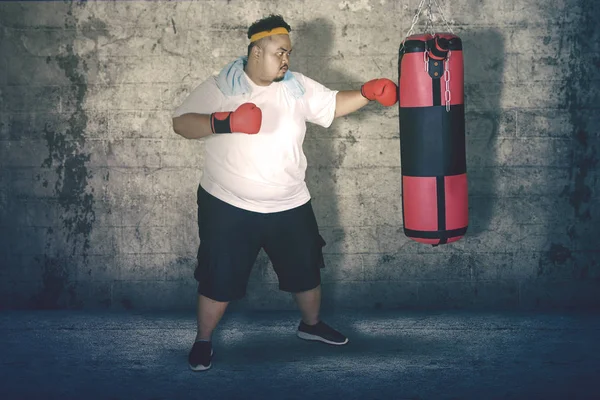 Picture Obese Man Punching Boxing Bag Exercising Studio — Stock Photo, Image