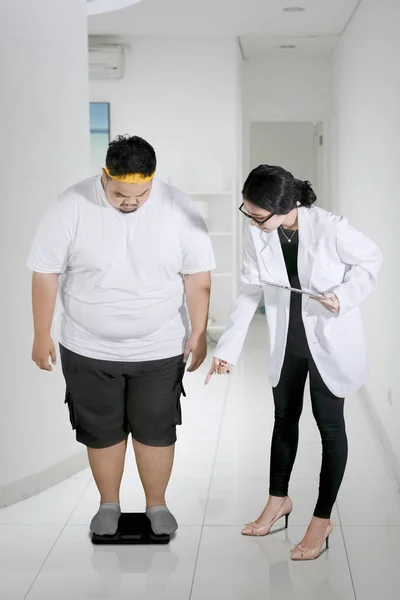 Retrato Una Médica Examinando Paciente Gordo Usando Escamas Mientras Sostiene — Foto de Stock