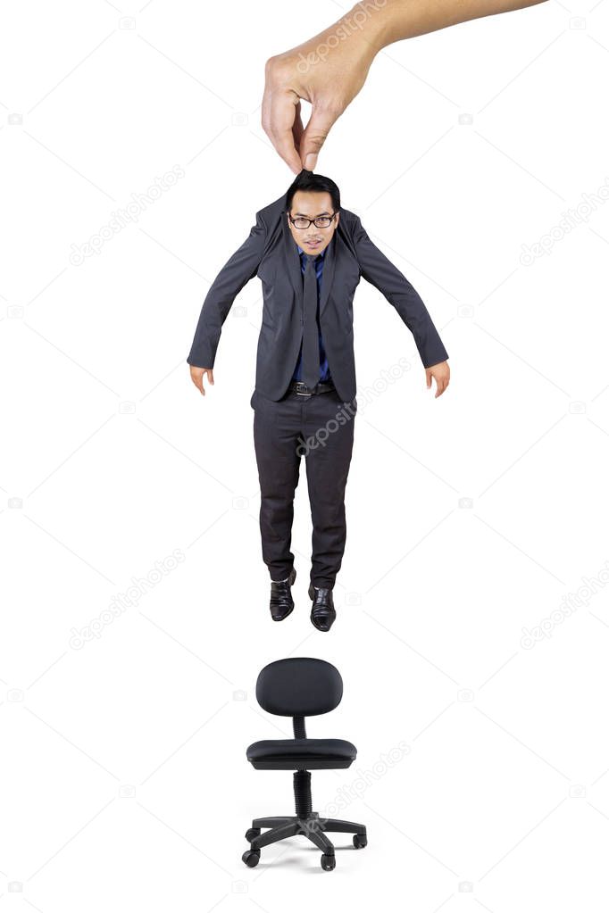 Picture of big hand puts an Asian businessman on a chair, isolated on white background