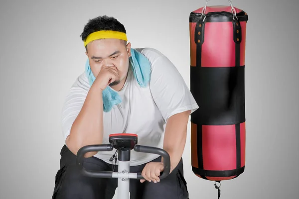 在演播室里用运动自行车锻炼后 满头大汗的胖子的照片看起来很累 — 图库照片