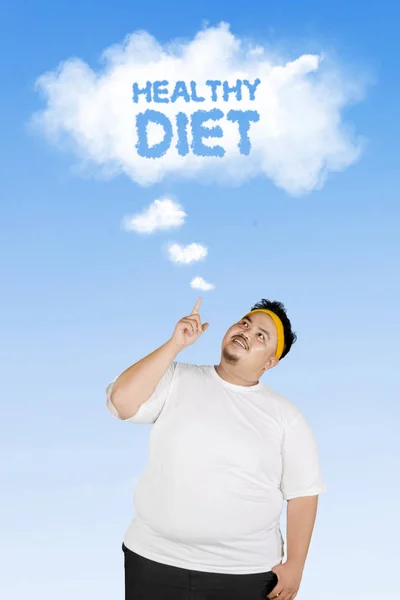 青い空の下で立っている間雲に健康的な食事のテキストでクラウドを指す若いデブ男のイメージ — ストック写真
