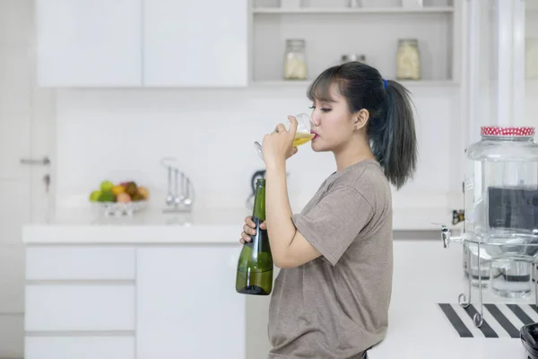年轻的亚洲妇女站在厨房里喝香槟酒 — 图库照片