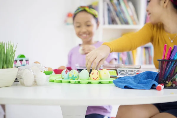 Petite fille guidée par sa mère pour teindre les œufs de Pâques — Photo