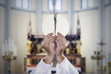 Hands of pastor holding a bright communion wafer clipart