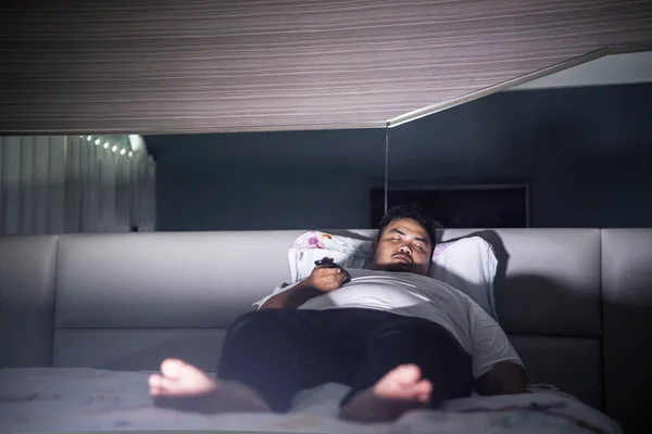 Grasso uomo si addormenta durante gli orologi TV sul letto — Foto Stock