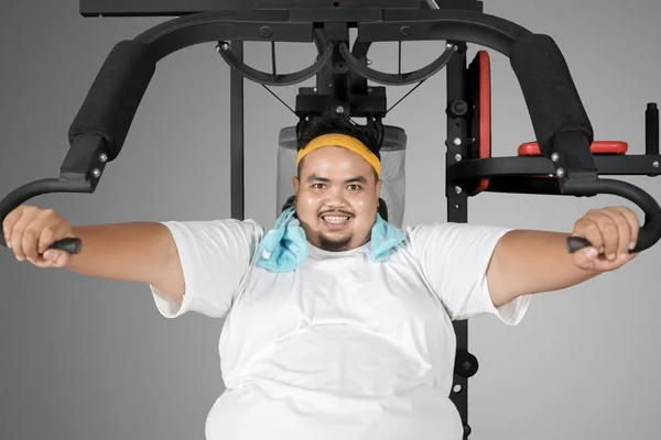 Hombre gordo feliz haciendo ejercicio con una máquina de fitness —  Fotos de Stock