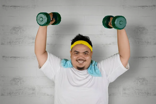Happy fat man lifting two dumbbells — Stock Photo, Image