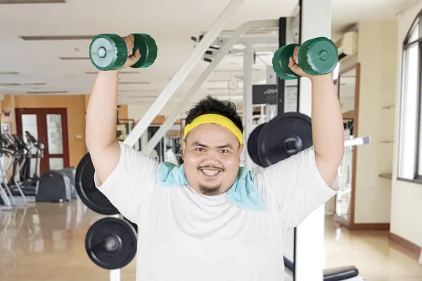 Happy fat man lifts dumbbells in gym center — Stock Photo, Image