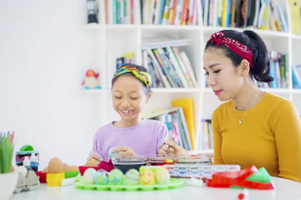 Little girl guided by her mother to dye Easter eggs — Stock Photo, Image