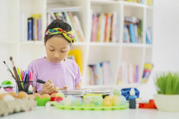 Κοριτσάκι που μαθαίνει να ζωγραφίσει Πασχαλινά αυγά στη βιβλιοθήκη — Φωτογραφία Αρχείου