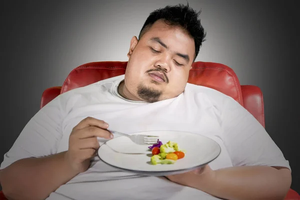 Grasso uomo infelice mangiare un piatto di cibo sano — Foto Stock