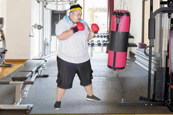 Молодой толстяк делает упражнения с боксерским мешком — стоковое фото