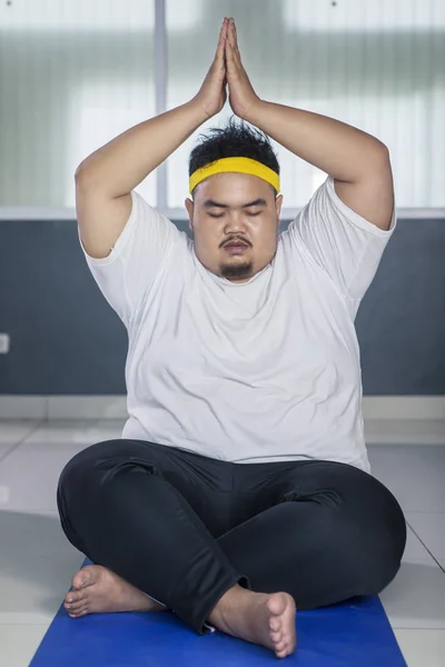 Young fat man doing yoga exercise on the mat — Stock Photo, Image