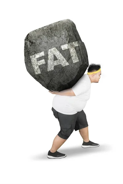 Young obese man carrying fat word on studio — Stock Photo, Image