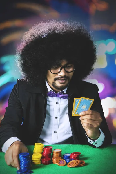 Young Afro man holds poker cards in the casino — Stock Photo, Image