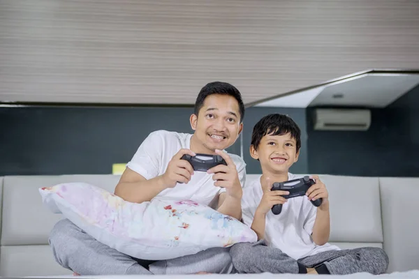 Jongen en zijn vader spelen videospel in slaapkamer — Stockfoto