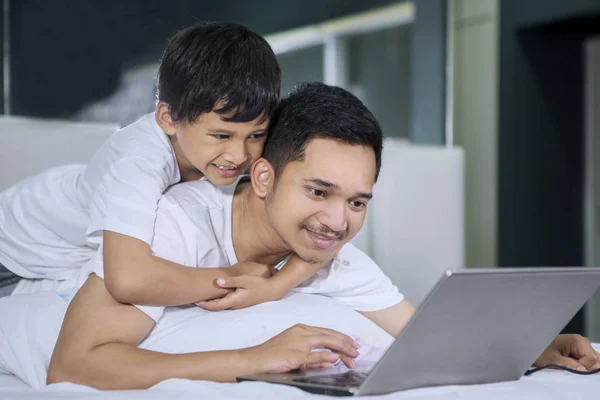 Adam ve oğlu yatağa dizüstü bilgisayar kullanan — Stok fotoğraf