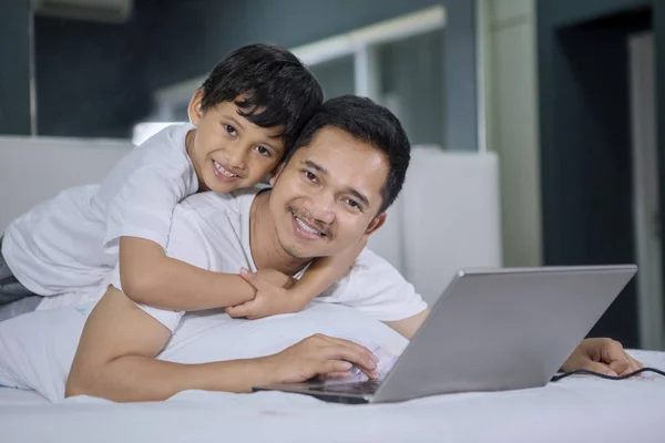 Człowiek i syn uśmiechając się aparatu podczas korzystania z laptopa — Zdjęcie stockowe
