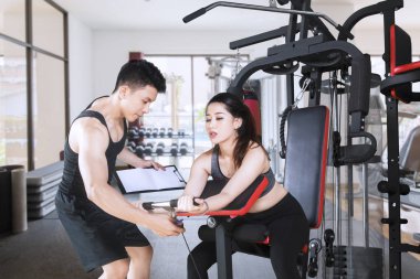 Genç antrenör spor salonunda eğitmek için onun müşteri yardımcı olur