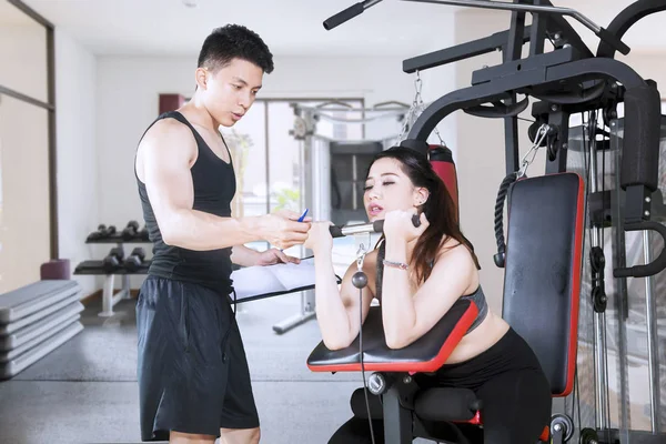 Mooie vrouw oefeningen met haar trainer op Gym — Stockfoto