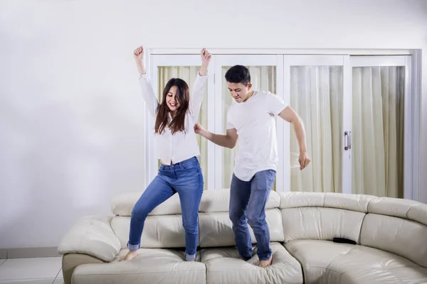 Cheerful couple dancing together on the couch — Stock Photo, Image