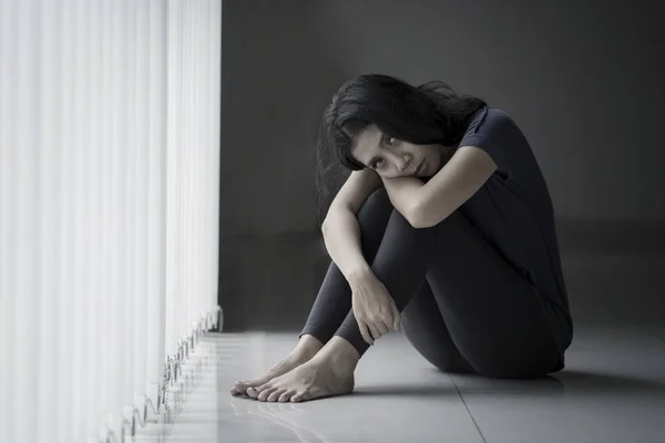 Einsame Frau sieht am Fenster ungesund aus — Stockfoto