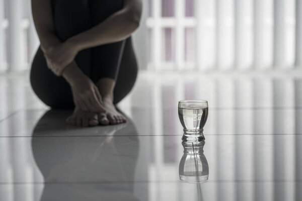 Lonely woman sitting with a glass of water