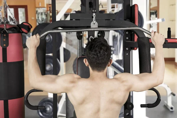 Muscular man doing workout with fitness machine — Stock Photo, Image