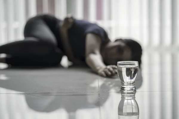 Sjuk kvinna kryper mot ett glas vatten — Stockfoto