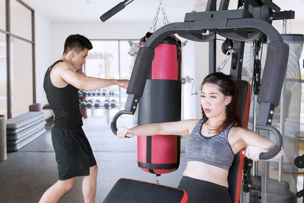 Pareja joven haciendo ejercicio en la máquina de peso — Foto de Stock