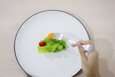Kadın el küçük porsiyon salata yiyor 