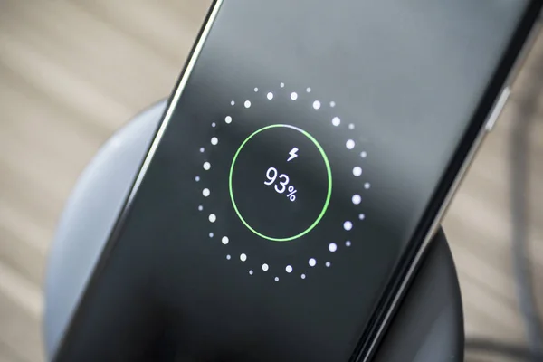 Black smartphone charging on a charging pad — Stock Photo, Image