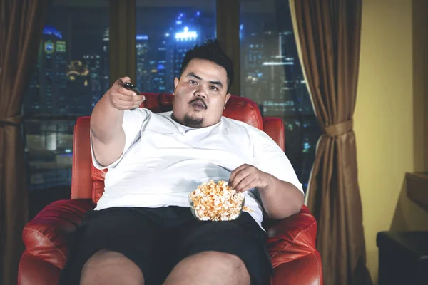 Fat man eats popcorn during watch television — Stock Photo, Image