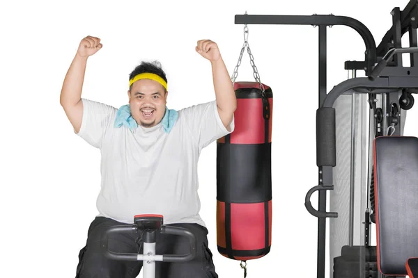 Fat man expresses happy on an exercise bike — Stock Photo, Image