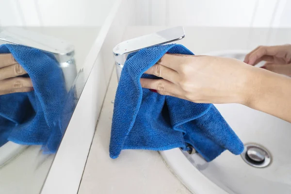 Hausmädchenhände reinigen Wasserhahn mit einem Lappen — Stockfoto