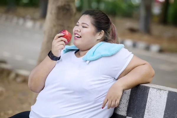 Nadváha žena, která jedla jablečné ovoce v parku — Stock fotografie