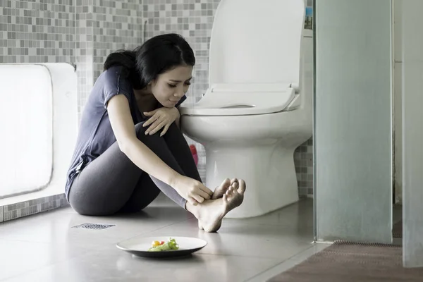 Droevige vrouw zittend met salade in de badkamer — Stockfoto