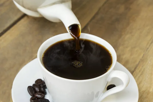 Ízletes kávé ömlött a fehér csésze asztalra — Stock Fotó