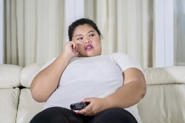 Femme en surpoids réfléchie regardant la télévision à la maison — Photo