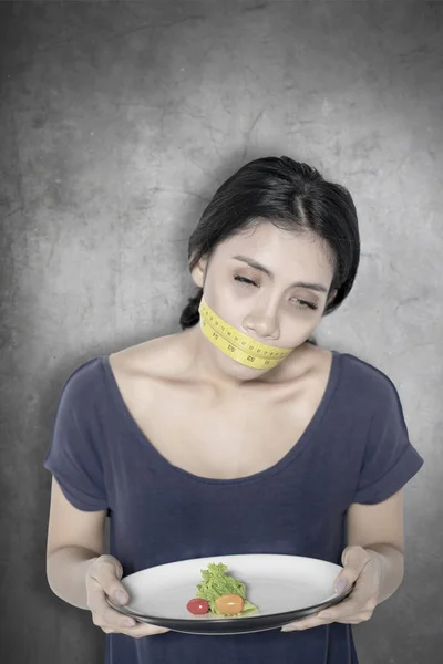 Tired woman with salad and measure tape — Stock Photo, Image