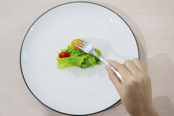 Unknown woman eats small portion salad 