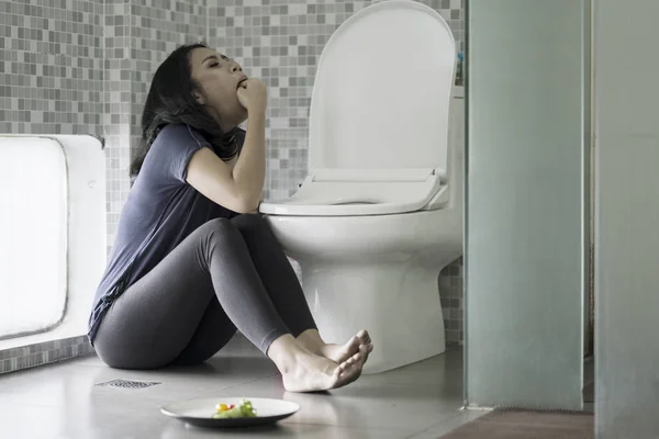 Vrouw dwingt zich te braken op de badkamer — Stockfoto