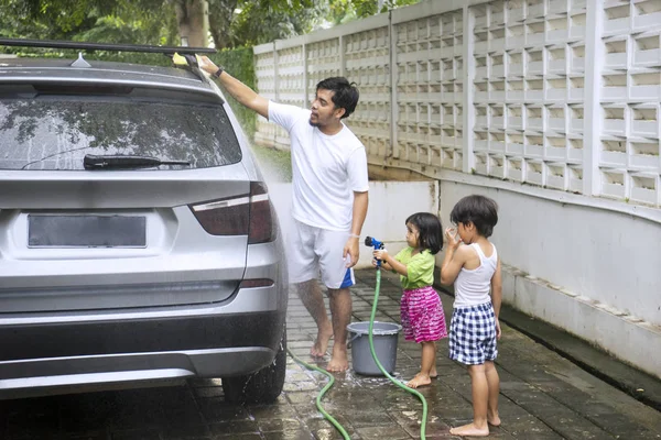 Pai e duas crianças lavam um carro em casa — Fotografia de Stock