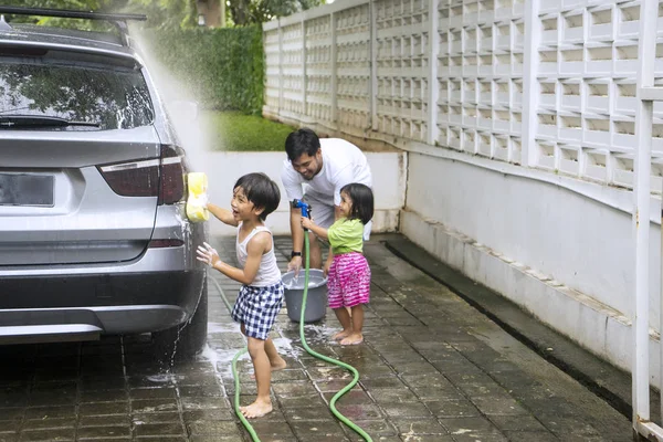 Niños pequeños ayudando a su padre a lavar un coche — Foto de Stock