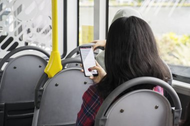 Bir telefonla otobüs içinde oturan kadın